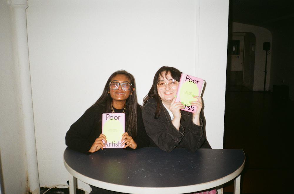 gab and zarina smiling together behind a small signing table