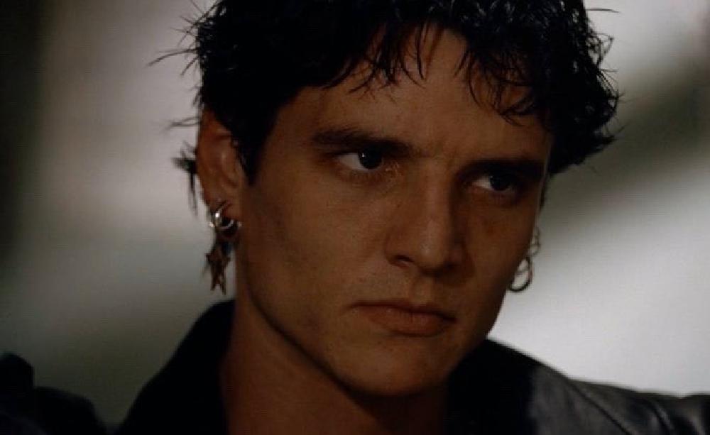 young pedro with dyed black hair and earrings scowling