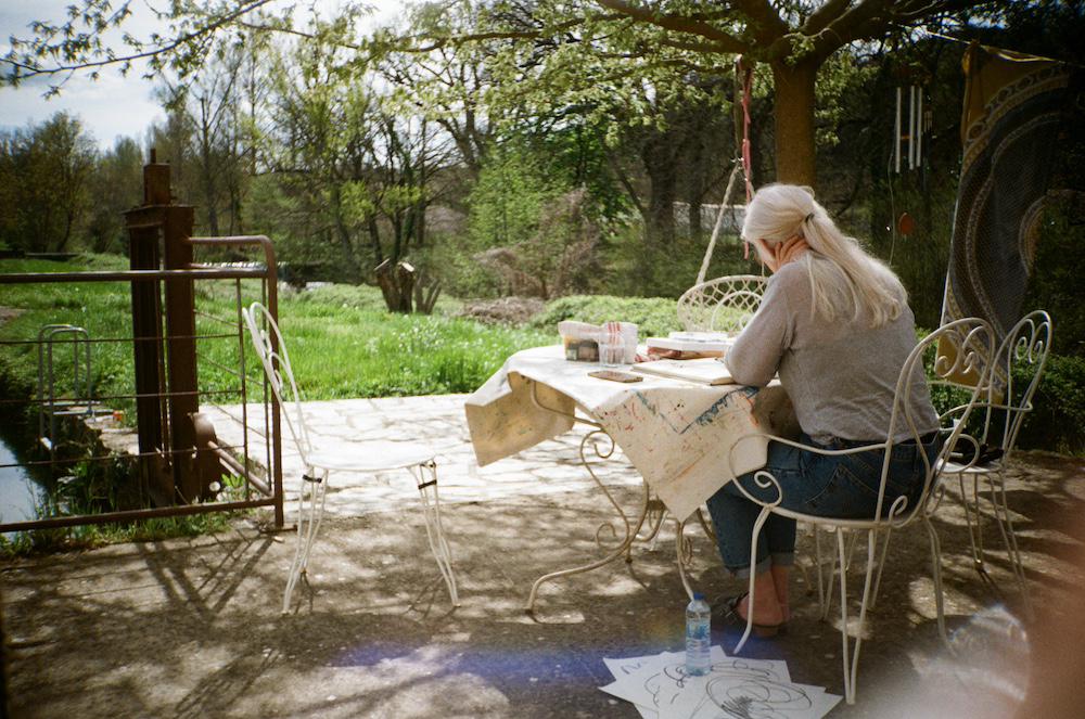 Anita working on some drawings at the table outside