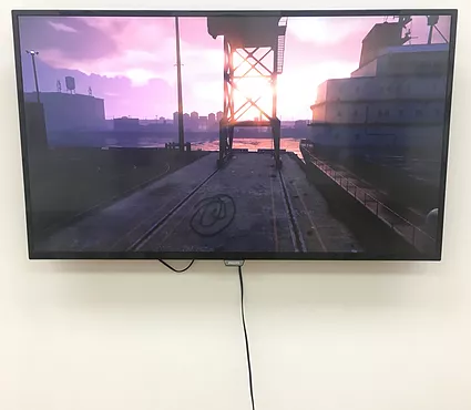 a video game shot of a dock with a container ship in the background