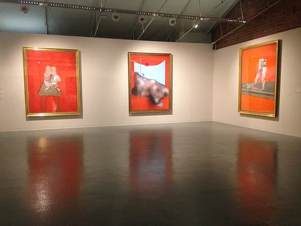 three huge bright orange paintings in gold frames by francis bacon depicting totally obscured bodies in white nude colours blurring together