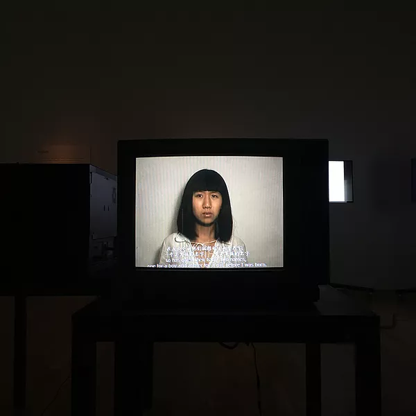 the artist on a CRT screen with a blunt hair cut and fringe