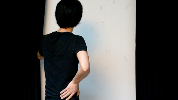 a man stands with a black shirt on and one hand on his hip