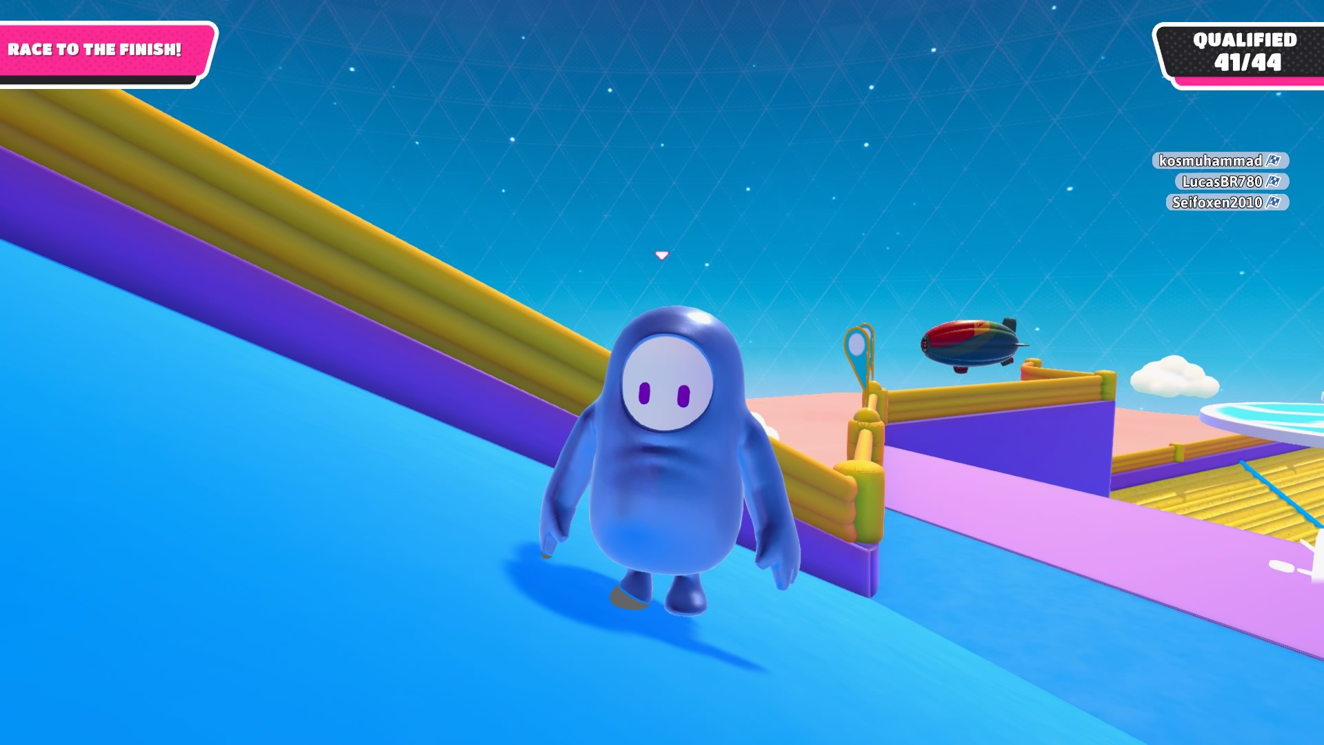 a blue bean with arms and legs and two little purple eyes for a face is stood on a slope against a blue starry background