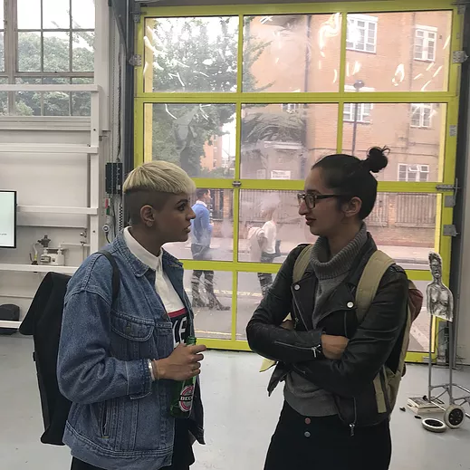 a painting of Seema and Amrita chatting in a gallery space with a big yellow framed door behind them