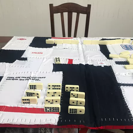 a table is covered with white and black materials, all stapled together, with rows of dominos on top