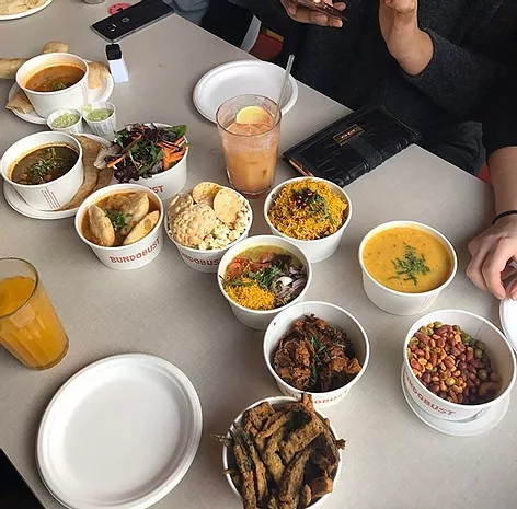 bowls of food are between two glasses with colourful drinks in