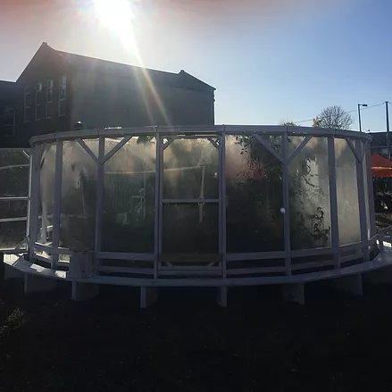 an outside shot of a green house that is made of white wood and screens