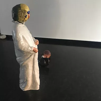 a ceramic bird is stood like a person wearing a room with small human hands