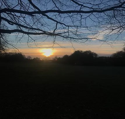 the sun is starting to set over a dark park no longer visible