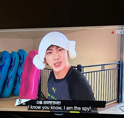 someone from BTS (sorry it is gabrielle writing this alt text not zarina and I have never listened to BTS so I also don&rsquo;t know their names ah) is looking at the camera saying I know you know, I am the spy, and he has a towel wrapped around his head